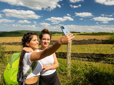 Holiday in the Eifel region with kids: action guaranteed Two women taking a selfie by a wooden fence in a sunny countryside setting