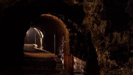 Eifel-Urlaub: Insidertipps aus Gemünd Dunkler unterirdischer Tunnel mit steinernen Bögen und Licht am Ende