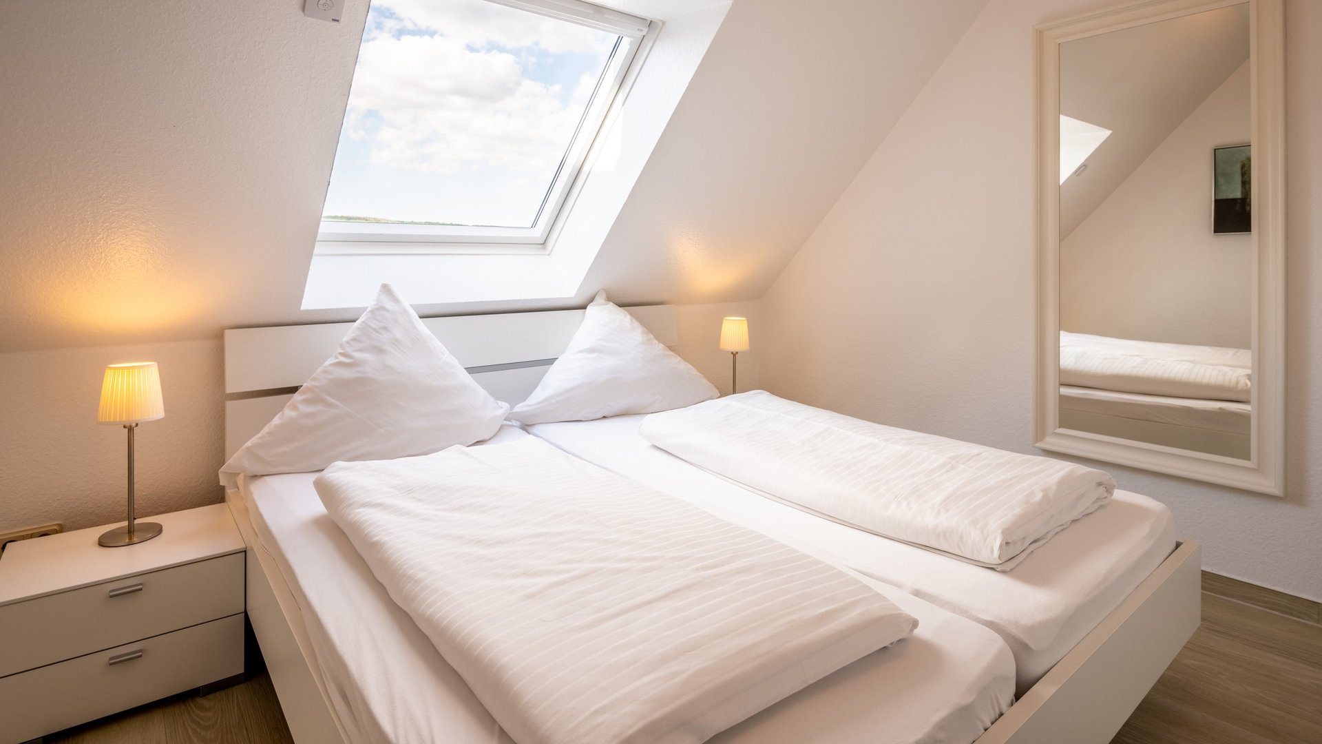 Holiday apartments in Gemünd with special flair Bright bedroom with skylight, double bed, and bedside tables with lamps