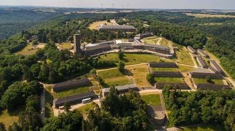 Ferien in der Eifel: ein erster Einblick Luftaufnahme eines großen historischen Gebäudekomplexes umgeben von Wald und Feldern