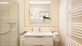 Urlaub in der Eifel mit Hund? Aber natürlich! Kleines Badezimmer mit Waschbecken, Spiegel, Handtüchern und Dusche