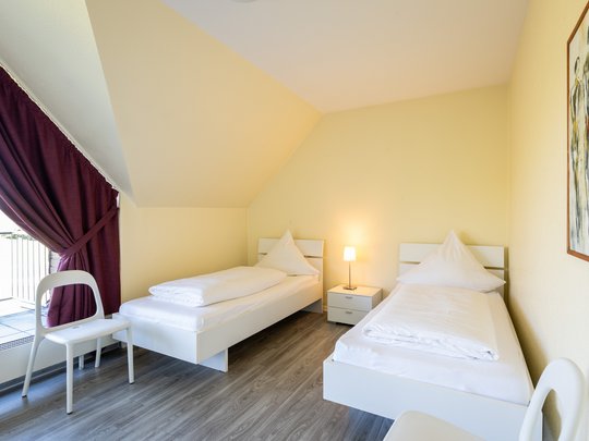 Ihre Unterkunft in Gemünd – Eifel-Urlaub voller Freiheit Hell eingerichtetes Schlafzimmer mit zwei Einzelbetten und Nachttischlampe