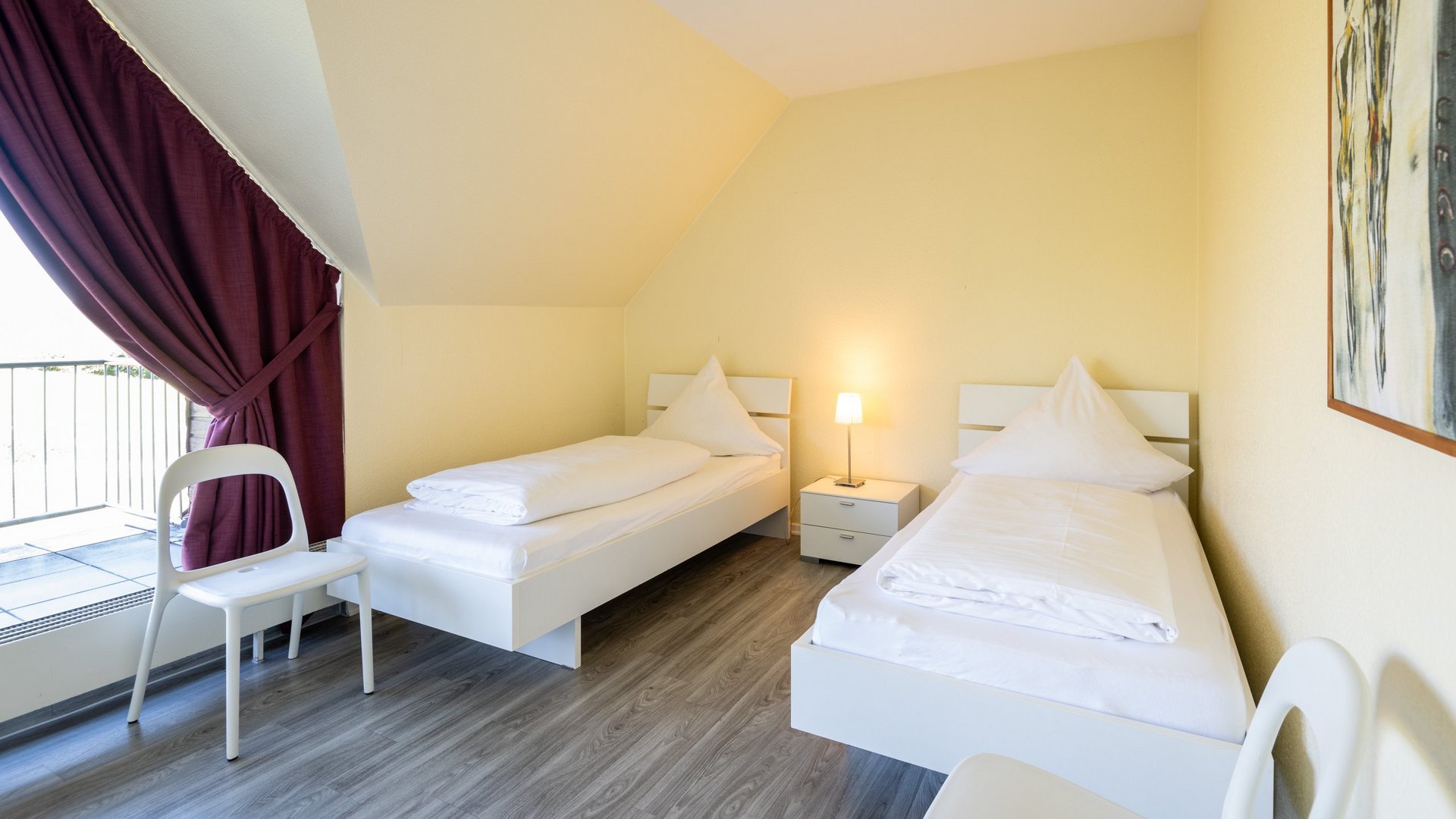 Ihre Unterkunft in Gemünd – Eifel-Urlaub voller Freiheit Hell eingerichtetes Schlafzimmer mit zwei Einzelbetten und Nachttischlampe