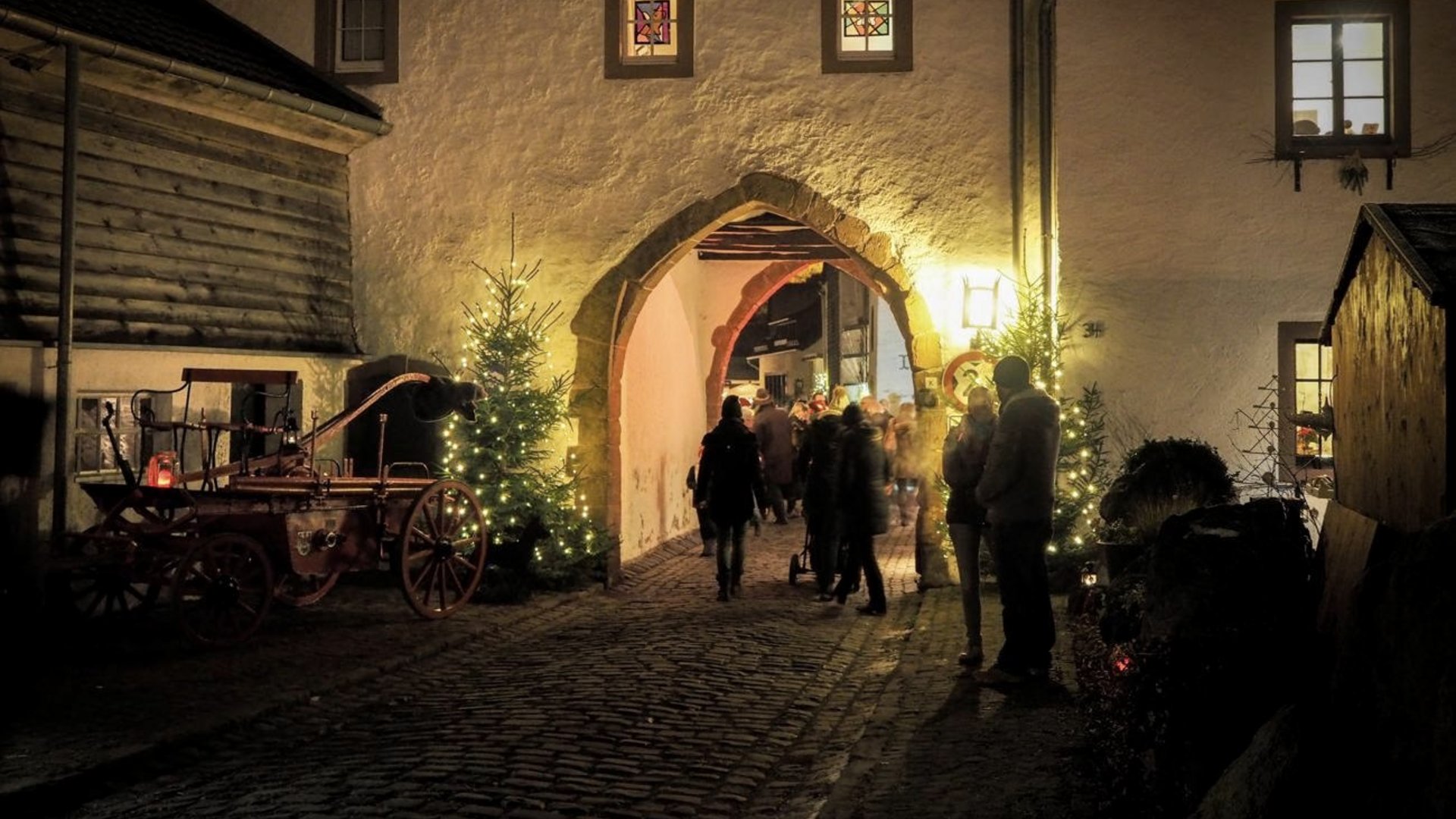 Eifel-Urlaub: Weihnachtsmärkte der Region Beleuchteter Torbogen mit Menschen und Weihnachtsbeleuchtung bei Nacht