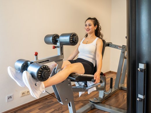 A holiday apartment in the Eifel region with a sauna and gym Woman exercising legs on leg extension machine at gym