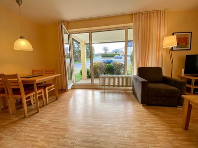 Ihre Unterkunft in der Eifel – Urlaub mit Hund Heller Wohnbereich mit Esstisch, Sessel und bodentiefem Fenster zur Straße