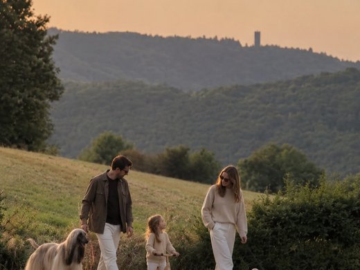 Ihre Unterkunft in der Eifel – Urlaub mit Hund Familie mit zwei Hunden und Laufrad beim Spaziergang in hügeliger Landschaft