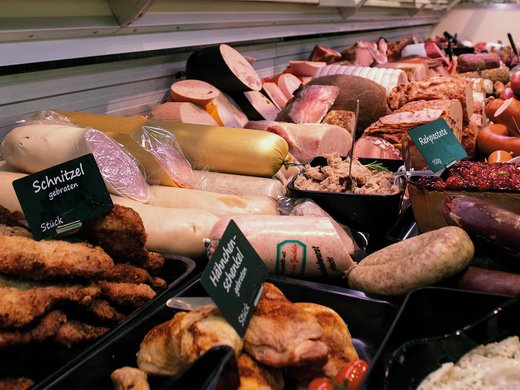 Experience flavour instead of just reading about it – exclusively for our guests Display case with various meat and sausage products in a butcher shop