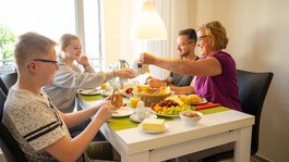 Urlaub in der Eifel mit Hund? Aber natürlich! Familie beim Frühstück mit Brot, Obst und Tee am Esstisch