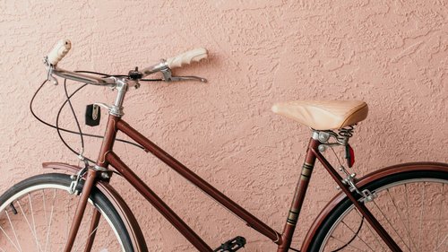 Ihre Wohnung in Gemünd in der Eifel: jetzt anfragen! Rotes Vintage-Fahrrad vor texturierter rosa Wand