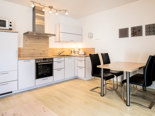Ihre Unterkunft in Gemünd – Eifel-Urlaub voller Freiheit Moderner Küchenbereich mit Esstisch und schwarzen Stühlen