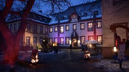 Weihnachtsmarkt in Kloster Steinfeld, © Kloster Steinfeld Weihnachtlicher Innenhof mit beleuchtetem Baum und brennenden Feuern am Abend