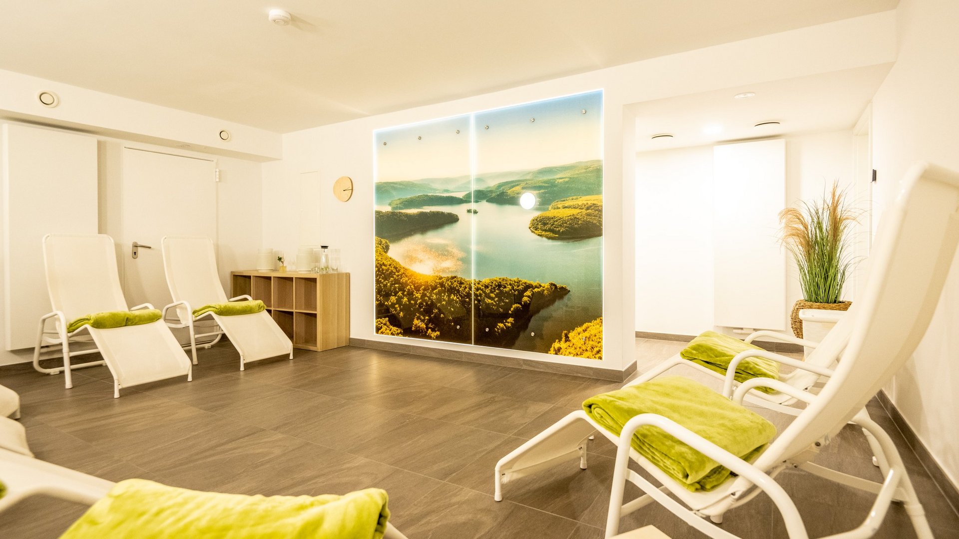 A holiday apartment in the Eifel region with a sauna and gym Relaxation room with lounge chairs and landscape photo on wall