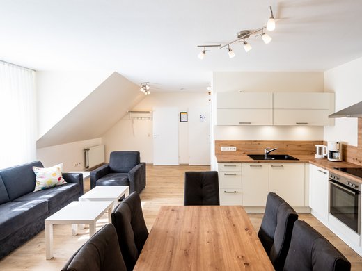 Ihre Unterkunft in Gemünd – Eifel-Urlaub voller Freiheit Helle moderne Wohnküche mit Esstisch, Küche und Sitzecke unter Dachschräge