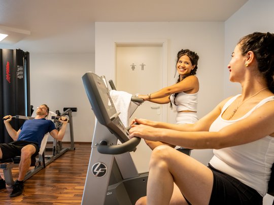 Alle aktuellen Angebote, Specials und Raten im Gemünder Ferienpark Salzberg – perfekt für euren Urlaub im Nationalpark Eifel. Drei Personen trainieren in einem Fitnessstudio an verschiedenen Geräten.